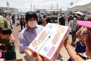 当たりくじ付き餅まきの特賞桃1ケースを受け取る様子