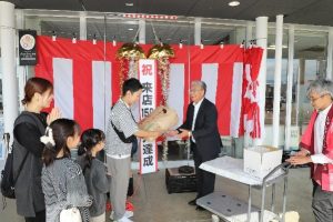宮越さんに令和7年産あきたこまち玄米30キロと管内産のシャインマスカット1房が贈られる様子